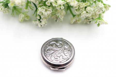 Caixa de comprimidos circular em prata com relevos vegetalistas na tampa